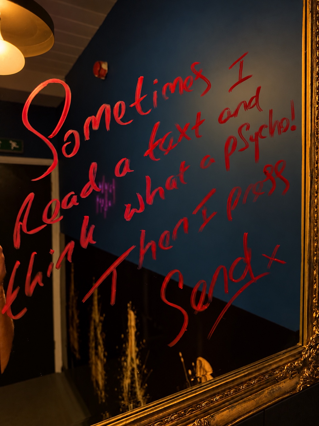 Gold-framed mirror inside PRIV with a playful handwritten message in red.